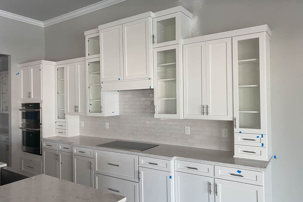 Sleek white custom kitchen cabinets with glass inserts and modern hardware in a bright kitchen setting in North Port, FL.