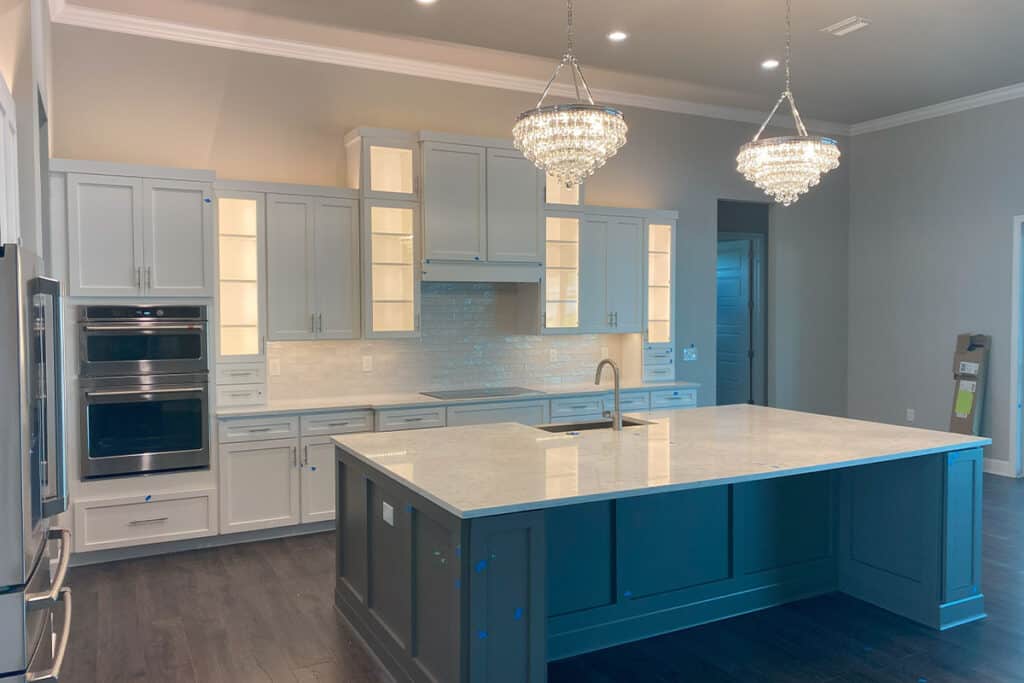 Elegant kitchen cabinets illuminated with built-in lighting, surrounding a large kitchen island with marble countertops in North Port, FL.