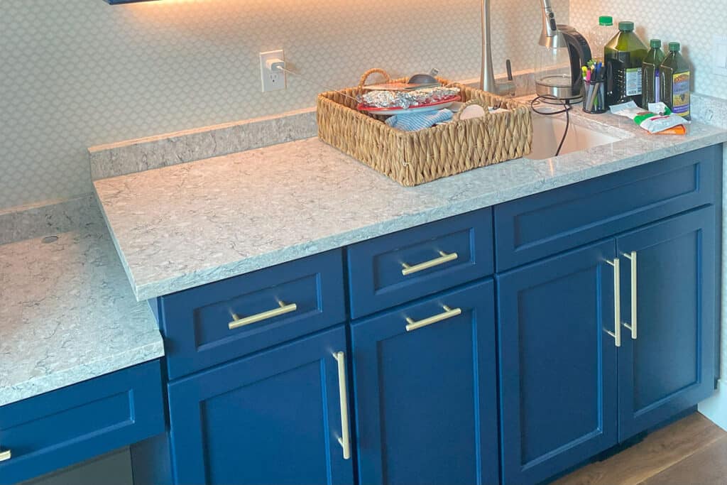 Stylish blue kitchen cabinets with gold handles and a marble countertop in a cozy kitchen space in North Port, FL.